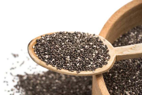 Tahta kaşık bazı yayılan konuşabilerek yukarıda da görüleceği bulanık beyaz arka plan üzerinde ahşap bir kaseyle üstüne chia tohum yakın çekim