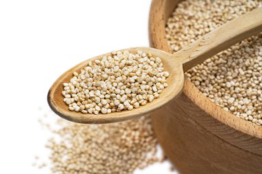 Üst ve beyaz arka planda konuşabilerek yukarıda da görüleceği izole bir kaşık ile ahşap bir kabın içinde Quinoa tohumların yakın çekim