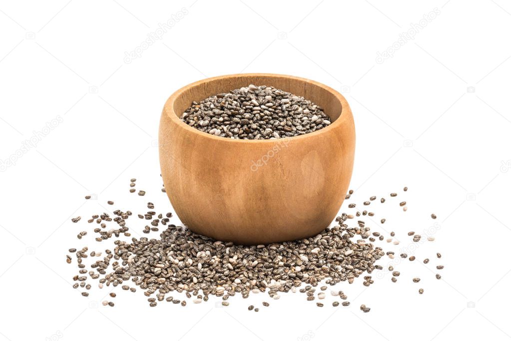 Chia seeds in small wooden bowl with some spilled in front of it seen from the side and isolated on white background