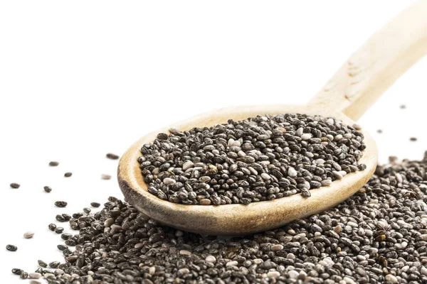 Chia tohum ve eğik sol üst köşede ücretsiz white boşluktan ön görülen bir tahta kaşık yığını 