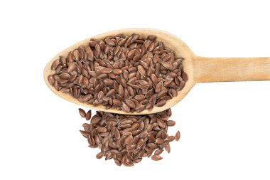 Tahta bir kaşığa keten tohumu ya da keten tohumu koyun. Yanındaki kazık doğrudan yukarıdan görünür ve beyaz arka planda izole olur.