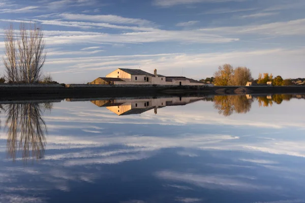 Bir lagün üzerindeki bir çiftliğin görüntüsünden oluşan arka plan, içinde açıkça yansıtılır.
