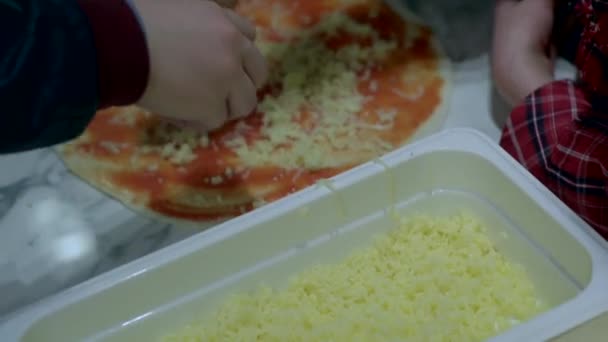 Baby handen vullen de kaas op de pizza korst — Stockvideo