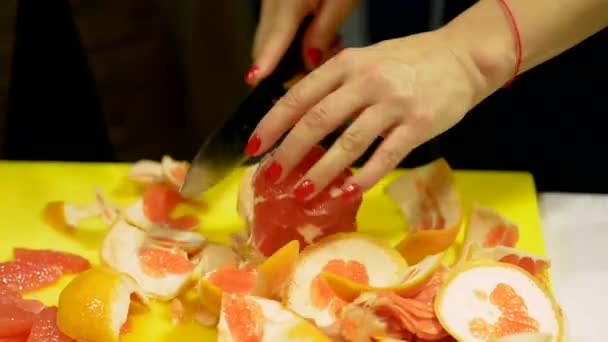 Las manos de las mujeres cortan el pomelo pelado en trozos . — Vídeos de Stock