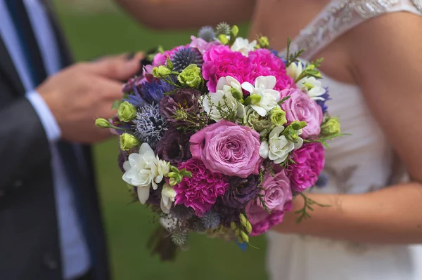 Buquê de casamento em tons rosa contra o fundo da noiva e do noivo — Fotografia de Stock