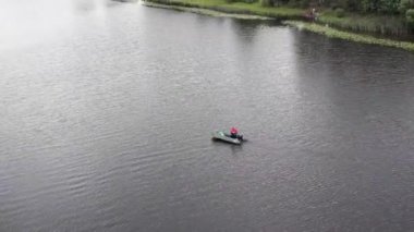 Lastik bottaki bir balıkçı nehirde yüzüyor.