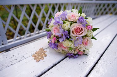 pembe ve leylak tonları düğün buketi, bir park bankında yatıyor