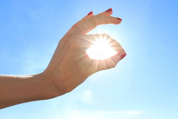 The sun in the hand of a girl who shows the gesture 