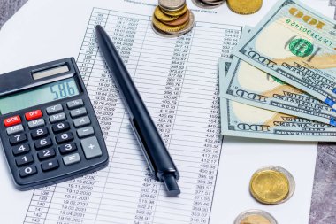 İpotek ve kredi ödemelerinin bir hesap makinesi ve gri arka plan üzerindeki banknotlarla hesaplanması