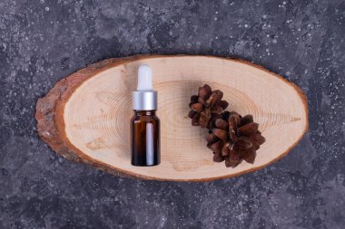 Kolajenle nemlendirici serum ve yüz derisi için sümüklü salyangoz, kırışıklıklara ve kırışıklıklara karşı cam bir şişede, tahta bir stantta ve gri bir masada koniler.