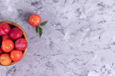 Kopyalama boşluğunda ahşap bir tabakta olgun kırmızı erikler