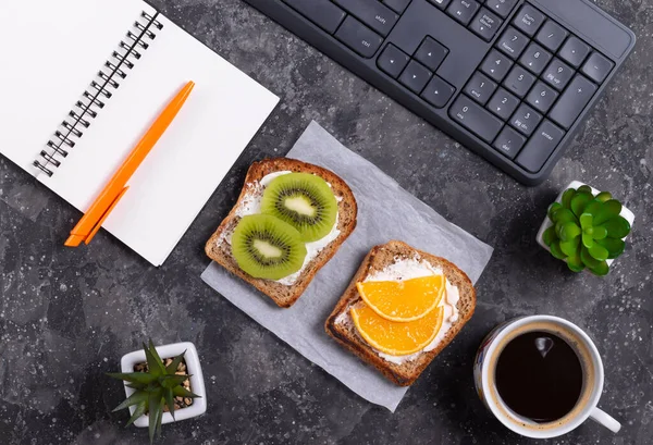 Healthy snack fruit sandwiches and black coffee at the workplace in the office at the computer