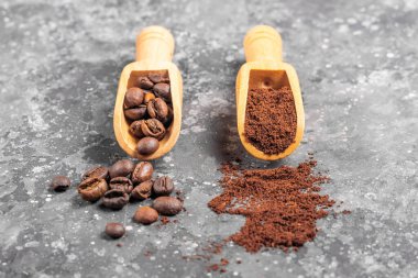 Kahve çekirdekleri ve kahve, gri arka planda tahta küreklerde.