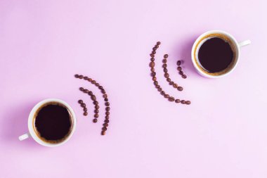 Espresso fincanları, pembe arka planda kahve çekirdeklerinin kablosuz izi.