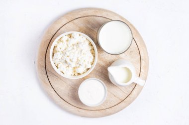 Tahta süzme peynir, krema, süt ve ekşi krema beyaz arka planda ahşap bir tezgahta