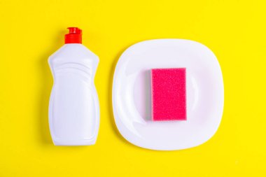 Sarı arka planda bulaşık suyu, tabak ve pembe sünger.