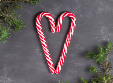 Tebeşir arkaplanındaki kırmızı ve beyaz değneklerden yapılmış kalp köknar dallarıyla