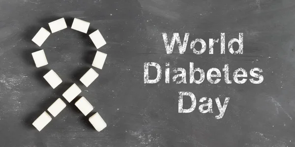 World Diabetes Day lettering in chalk on a gray background with sugar cubes
