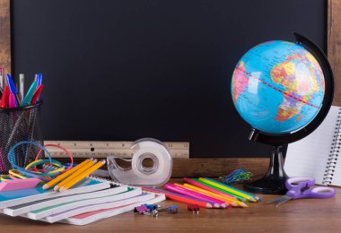 Okul malzemeleri için arkasında kopya alanı için arka planda boş yazı tahtası ile ahşap bir masaüstü ürün yelpazesine