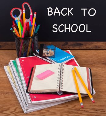 Okul defter kalem geri için arka planda bir kara tahta üzerinde yazılı Scool ile ahşap bir masaüstü ile