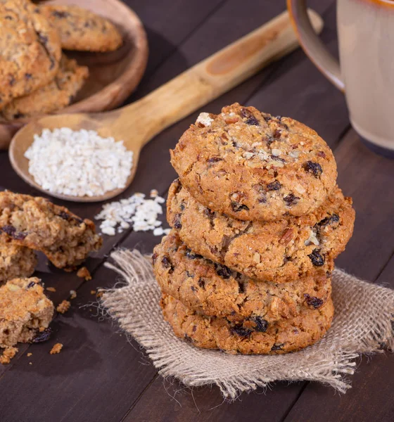 Stack of raisin pecan oatmeal cookies with a spoonful of oatmeal flakes in background