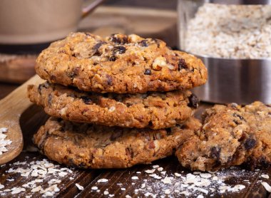 Closeup of a stack of oatmeal raisin nut cookies and oatmeal flakes on a rustic wooden surface