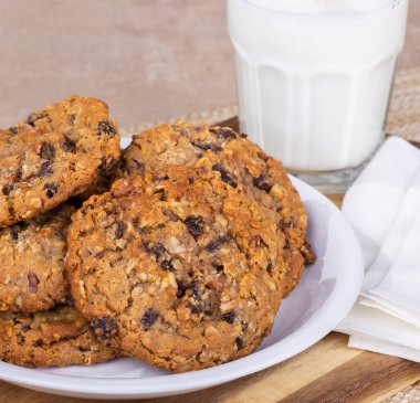 Arka planda bir bardak süt ile bir tabak üzerinde yulaf ezmesi kuru üzüm fındık çerezleri bir yığın Closeup