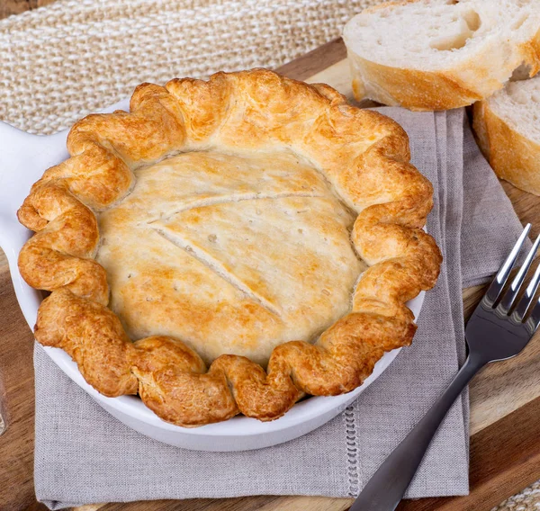 Overhead view of a chicken pot pie with golden crust in a white baking dish