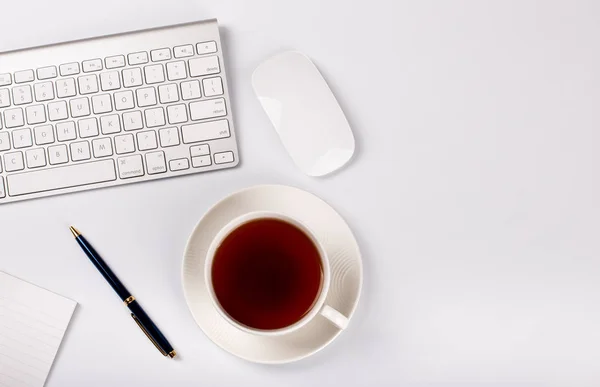 Weißer Desktop mit Tastatur, Maus und Tasse Tee — Stockfoto