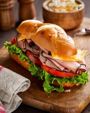 Denizaltı jambonlu ve peynirli sandviç, domates ve marullu tahta kesim tahtası.