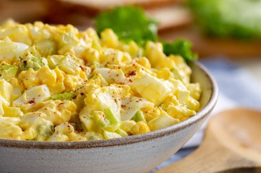 Ekmek dilimleri ve salatayla dolu bir kasede yumurta salatası.