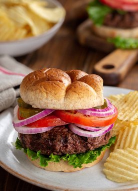 Marullu, domatesli, turşulu ve soğanlı sulu ızgara hamberger ekmeği ve patates cipsi.