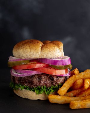 Salatalı, domatesli, turşulu ve soğanlı ızgara hamberger kepek ekmeği ve patates kızartması.