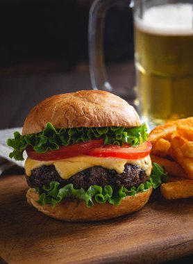 Sulu ızgara çizburger, marul, domates ve tahtadan yapılmış patates kızartması.