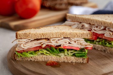 Hindili, domatesli ve marullu sağlıklı sandviç tahtanın üzerinde kepekli ekmek.