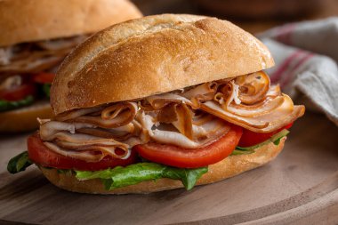 Tahta üzerinde hindi, domates ve marullu sağlıklı bir sandviç.