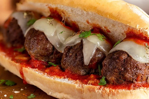 Closeup of a meatball sandwich with tomato sauce and cheese on a hoagie roll