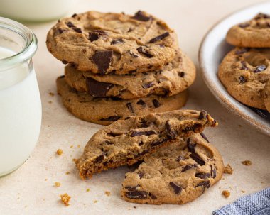 Çikolata parçacıklı kurabiyeler ve masanın üzerindeki bir bardak süt. 