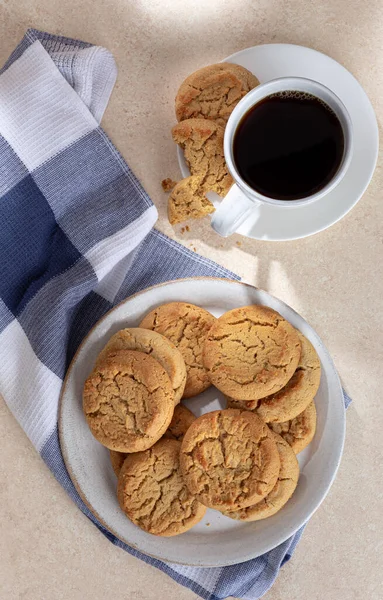 Overhead of peanut butter cookies on a plate and cup of coffee on a table