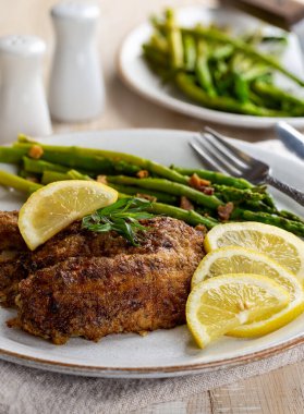 Fırında tilapia balığı filetosu dilimlenmiş limon ve kuşkonmaz.