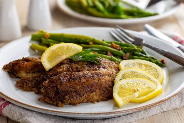 Fırında tilapia balığı filetosu dilimlenmiş limon ve kuşkonmaz.