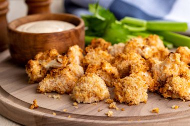 Havada kızartılmış karnabahar çiçekleri ve ahşap tepside çiftlik sosu.