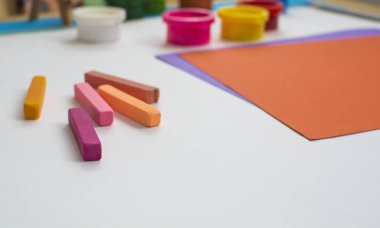 Renkli kağıt ve boyalar masanın üzerinde.