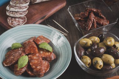Kase ve kurutulmuş domates ve zeytin ile kesme tahtası üzerinde Chorizo ve salam sosis. Bar yılbaşı için hazır. Vintage etkisi