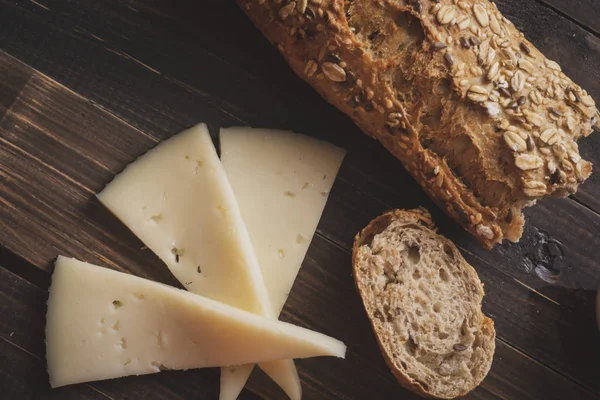 Ahşap masa İspanyol manchego koyun peyniri ve tahıllı ekmek en iyi görünümü. Vintage etkisi