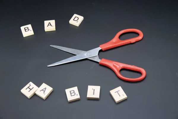 This picture show the scissors and the split word smoking. It represent use the will to quit the bad habit.