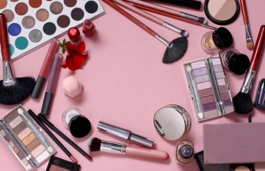 Pembe arka planda makyaj fırçaları ve kozmetik ürünleri
