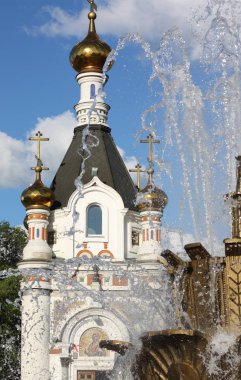 Ortodoks Kilisesi'nin arka planında Sovyet sembolleri olan şehir çeşmesi