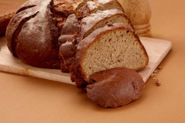 taze rustik kepekli çavdar ekmeği, ahşap bir tahta üzerinde dilimlenmiş,