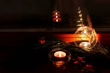 Noel arkaplanı. Pencerenin üzerinde bir mum duruyor, camda güzel bir yansıma. Çam dalı, oyuncaklı Noel ağaçları. Kırmızı yıldızlar.